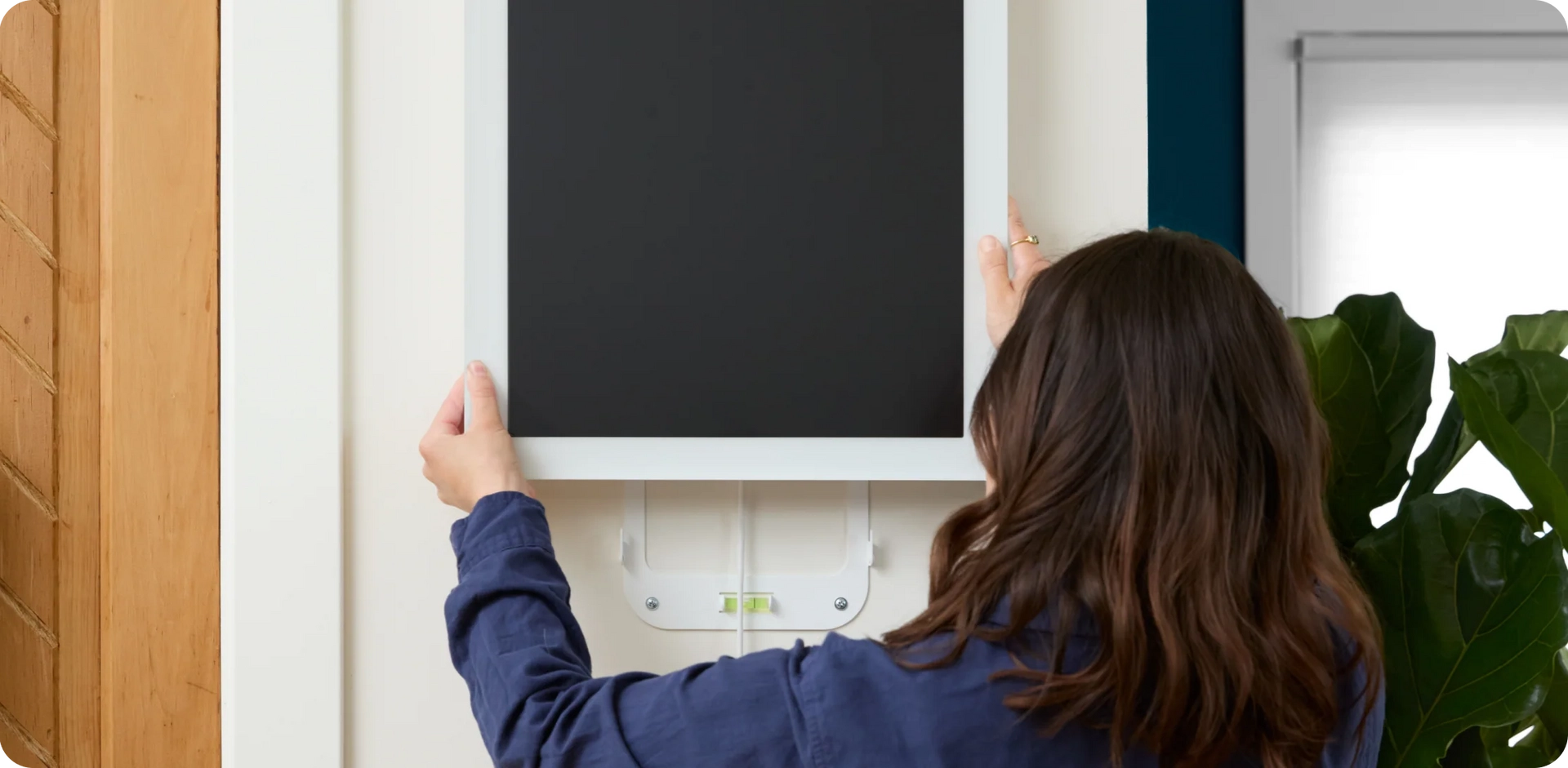 Women mounting a calendar max on the wall using a wall bracket, highlighting easy installation